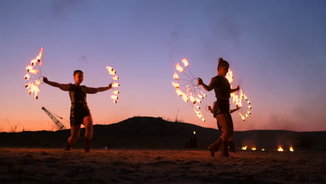 Artistas-Profesionales-Muestran-Un-Espectáculo-De-Fuego-En-Un-Festival-De-Verano-En-La-Arena-A-Cámara-Lenta.-Los-Acróbatas-De-La-Cuarta-Persona-Del-Circo-Trabajan-Con-Fuego-Por-La-Noche-En-La-Playa.